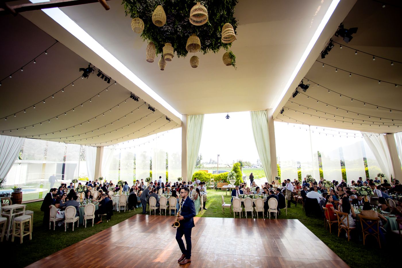 Recepción de boda bajo carpa en jardín con invitados