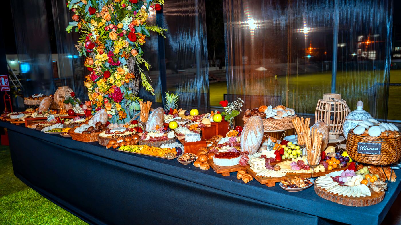 Mesa de buffet completa con panes, quesos y flores